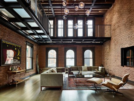 Expansive loft space with exposed brick walls, arched windows, and modern furnishings.