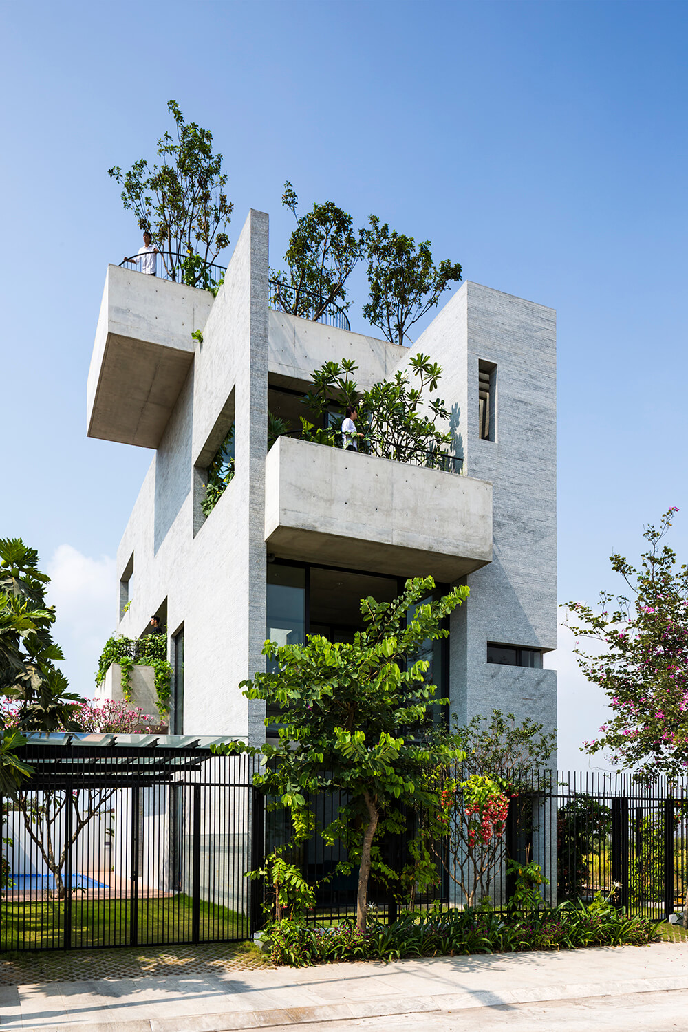 Striking concrete building with lush landscaping, featuring balconies and modern architectural elements.