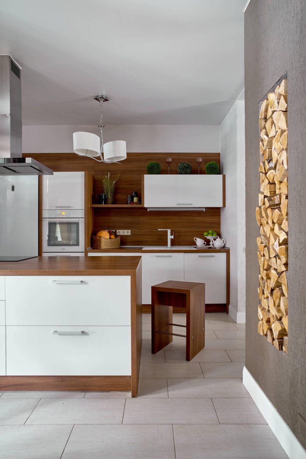 Sleek modern kitchen with wooden cabinetry, pendant lights, and a stack of firewood.