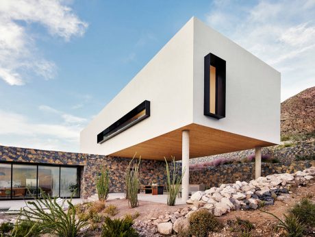 A striking modern structure with clean lines, contrasting textures, and an elevated terrace.