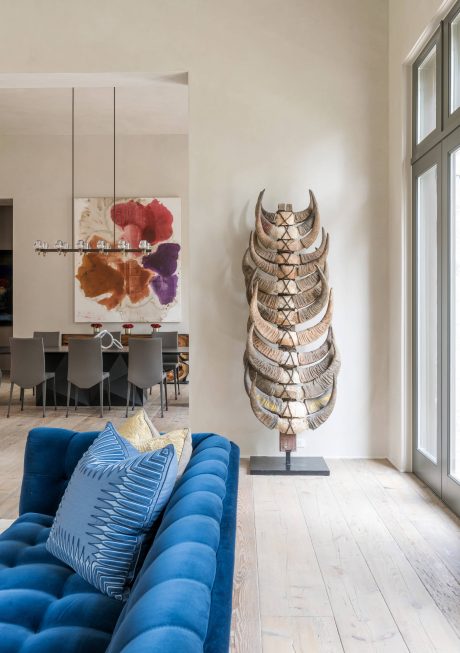 Vibrant living room with bold blue sofa, sculptural decor, and abstract artwork.