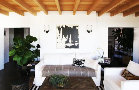 Rustic wooden ceiling beams, minimalist white decor, and patterned textiles create a cozy ambiance.