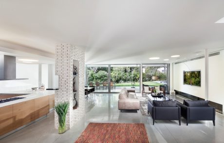 Expansive open-concept living space with large windows, sleek furnishings, and a brick accent wall.