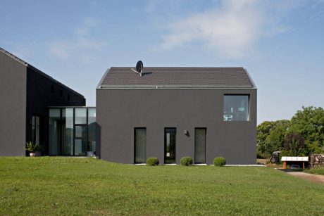 Modern, minimalist exterior with sleek lines, large windows, and a satellite dish atop the roof.