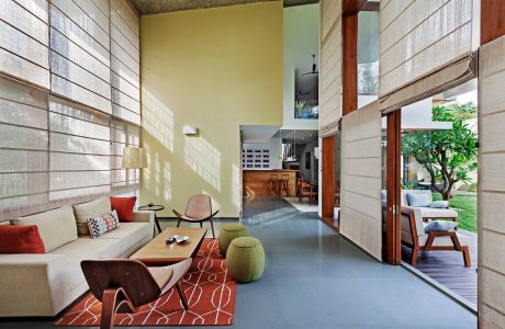 Spacious, modern living room with wooden walls, vibrant rug, and glass doors leading to patio.