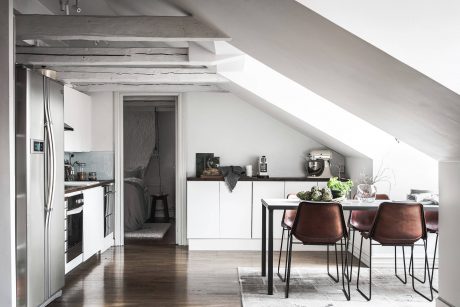 Modern, minimalist kitchen and dining area with white cabinets, wood accents, and sleek furniture.