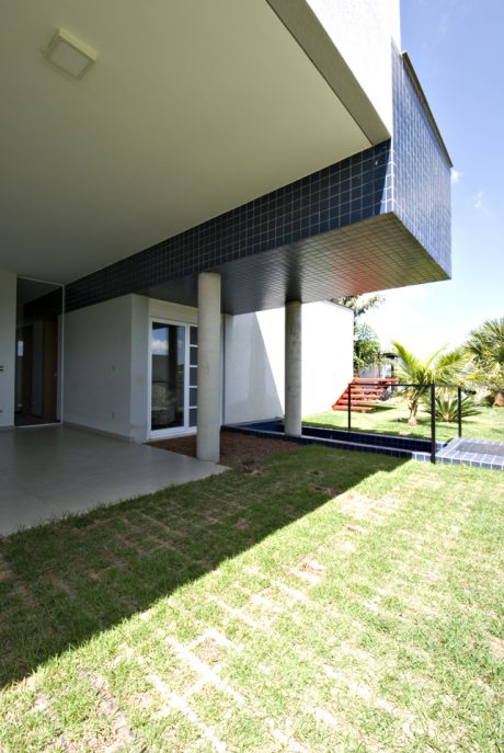 Modern architectural design with clean lines, textured exterior, and lush landscaping.