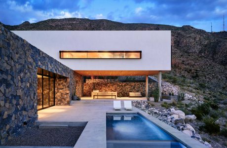 Stunning modern desert home with sleek architecture, pool, and stone walls.