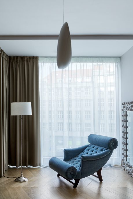 Luxurious lounge chair with tufted cushions set against a wall of sheer curtains.