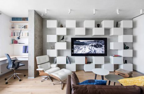 Sleek, modern living space with geometric shelving, TV, and comfortable seating.