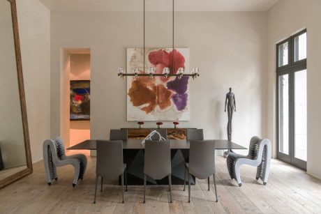 Elegant dining room with modern furniture, abstract artwork, and unique lighting fixture.