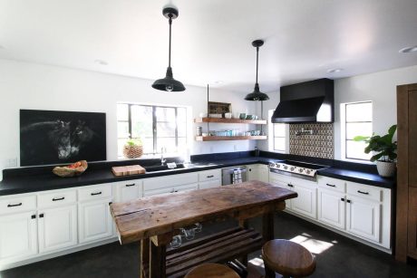 Modern rustic kitchen with white cabinets, black countertops, and a wooden island.