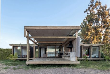 Modern wooden house with expansive covered deck and large windows overlooking nature.