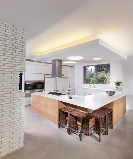 Modern open-concept kitchen with sleek white cabinets, warm wood island, and natural lighting.