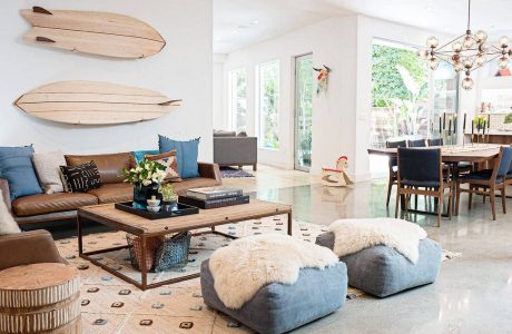 Coastal-inspired great room with surfboard decor, plush seating, and a rustic dining area.