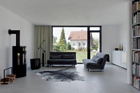Spacious modern living room with large windows, sleek furniture, and built-in bookshelves.