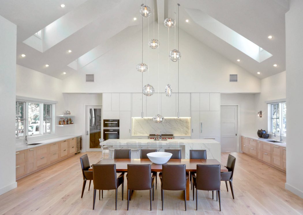 Spacious open-concept kitchen and dining area with vaulted ceiling, pendant lighting, and modern furnishings.