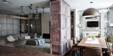 An expansive and rustic living space with wooden columns, intricate light fixtures, and a focal fireplace.