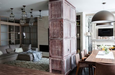 An expansive and rustic living space with wooden columns, intricate light fixtures, and a focal fireplace.