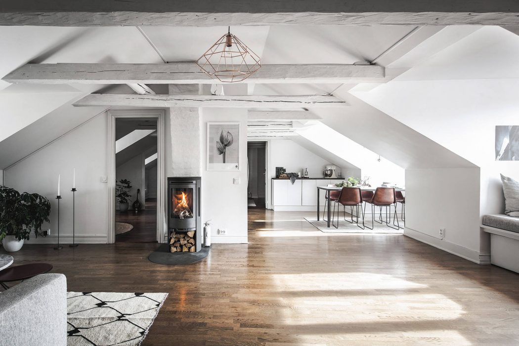 Cozy attic-like space with exposed wooden beams, wood floors, and a fireplace.