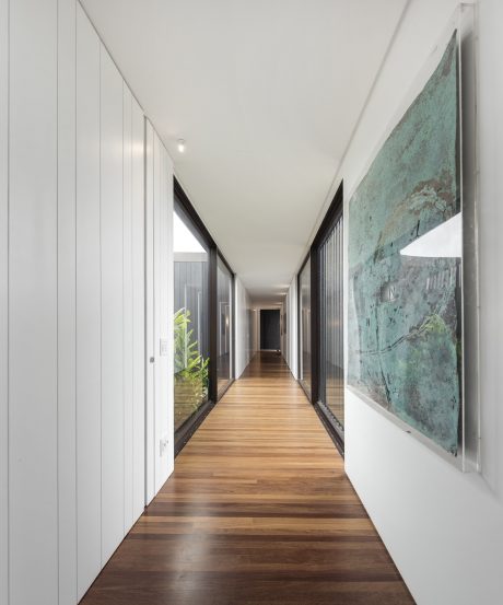 Sleek, modern hallway with wooden floor, white walls, and abstract artwork.