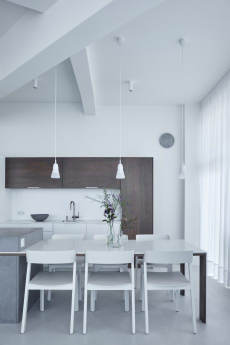 Minimalist kitchen with sleek cabinetry, pendant lighting, and a simple dining setup.