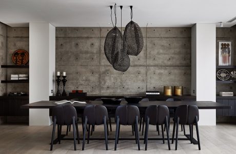 Minimalist dining room with monochrome decor, concrete walls, and striking pendant lights.