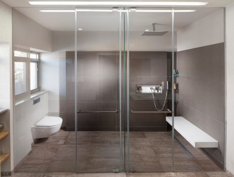 Modern, minimalist bathroom with glass shower enclosure, tiled walls, and floating vanity.
