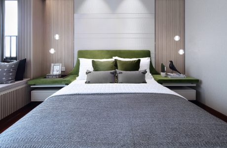 A contemporary bedroom with a green upholstered headboard, minimalist lighting, and patterned flooring.