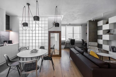 A modern, stylish living space with sleek furniture, lighting fixtures, and a glass block wall.