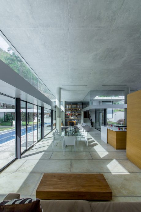 Large open-plan living area with concrete ceiling, glass walls, and modern furnishings.