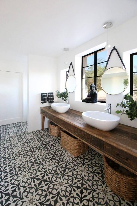 Rustic vanity with vessel sinks, round mirrors, and patterned tile floor in modern bathroom.