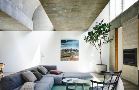 Spacious living area with exposed concrete ceiling, natural light, and modern furniture.