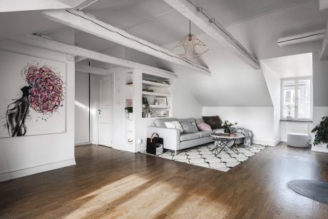 Spacious loft with modern decor, featuring exposed beams, hardwood floors, and abstract art.