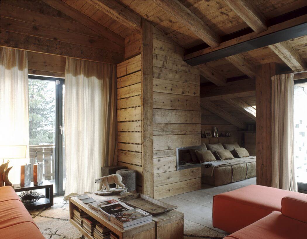 Cozy cabin interior with rustic wooden walls, exposed beams, and plush furnishings.