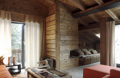 Cozy cabin interior with rustic wooden walls, exposed beams, and plush furnishings.