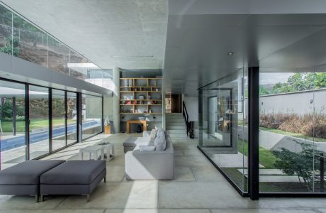 Sleek, minimalist living space with floor-to-ceiling glass walls, built-in shelving, and a modern fireplace.