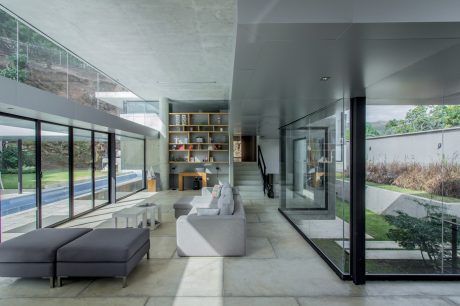 Sleek, minimalist living space with floor-to-ceiling glass walls, built-in shelving, and a modern fireplace.