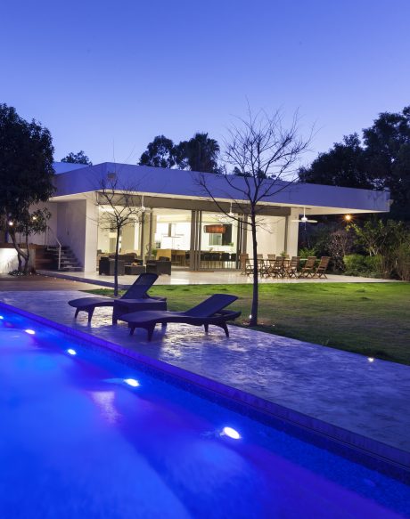 Sleek modern home with pool, patio, and illuminated landscape in a moonlit setting.