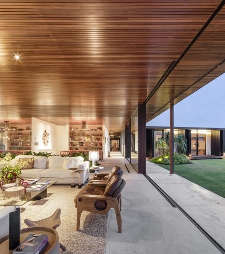 A modern, open-concept living space with a wooden ceiling, large windows, and a view of the outdoor garden.