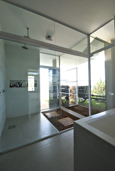 Modern bathroom with glass walls, sleek design, and natural lighting.