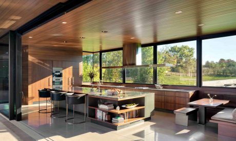 Elegant modern kitchen with floor-to-ceiling windows, wooden accents, and integrated shelving.