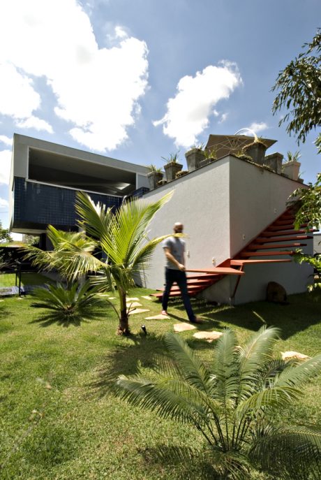 Modern tropical home with striking architectural features, lush palm-filled garden.