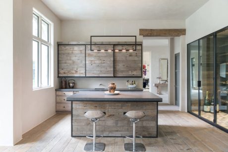 A modern rustic kitchen with wooden paneling, sleek lighting fixtures, and a central island.