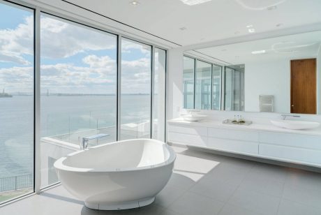 Sleek, modern bathroom with panoramic water views, large freestanding bathtub, and minimalist design.