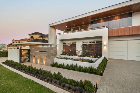 Modern luxury residential home with intricate architectural details, landscaping, and outdoor lighting.