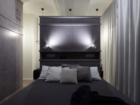 Sleek, modern bedroom design with dark gray accents, recessed lighting, and streamlined headboard.