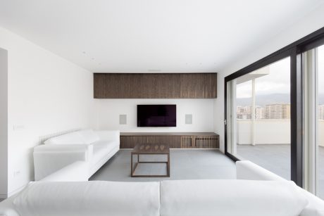 Minimalist living room with wooden accent wall, sleek furniture, and floor-to-ceiling windows.