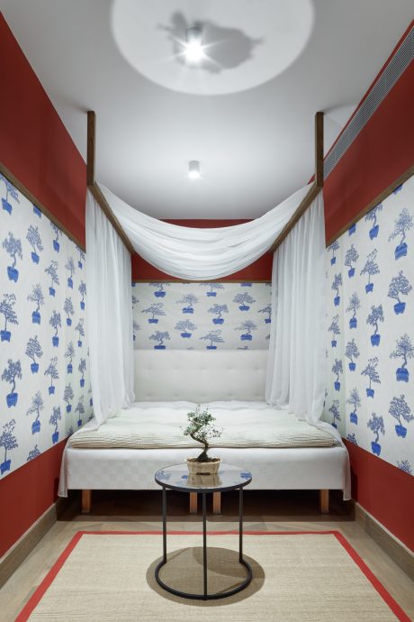 A minimalist bedroom with a bonsai tree, circular side table, and striped curtains.