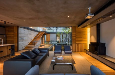 Warm, modern living space with wooden accents, glass walls, and a floating staircase.